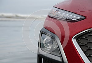 Headlamps of a red hatchback  on a beach in Ocean Shores