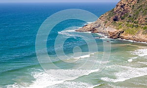 Headland jutting into the sea with railway tunnel and tracks next to bay photo