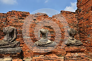 Headless Buddha images on the bases beside red brick wall