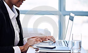 Headless crop of black businesswoman busy typing on notebook keyboard