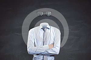 Headless invisible businessman with folded arms and abstract glasses standing on chalkboard wall background. Business and secret