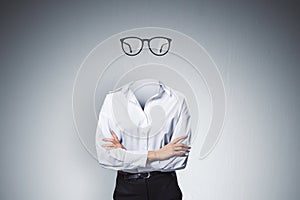 Headless invisible businesswoman with folded arms and abstract glasses standing on gray wall background. Business and secret