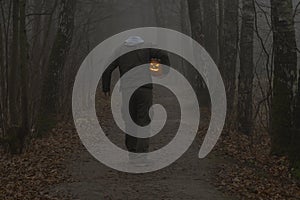 Headless man with Halloween pumpkin in foggy forest