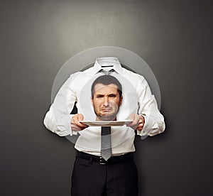 Headless man holding crying head on white plate