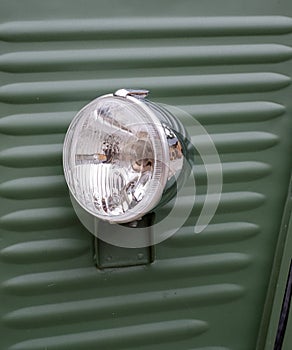 Headlight on the front of a retro green Citroen van.