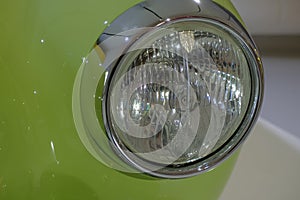 Headlight of a green retro car close-up. Car detail. Transportation. Car repair