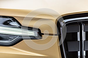 Headlight and grille details og a golden Polestar 1 hybris sports car..