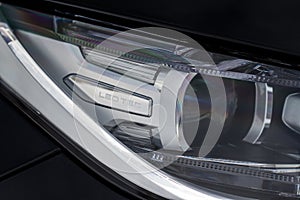 Headlight lamp of new cars. Close up detail on one of the LED headlights modern black car. Exterior closeup detail.