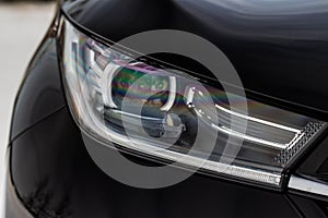 Headlight lamp of new cars. Close up detail on one of the LED headlights modern black car. Exterior closeup detail.