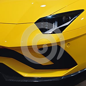 Headlight of a modern yellow sport car. The front lights of the car. Modern Car exterior details.