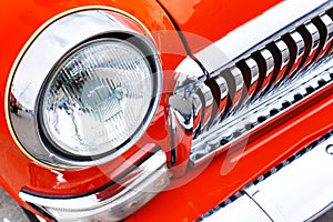 Headlight of a red retro car. Demonstration of the old auto industry