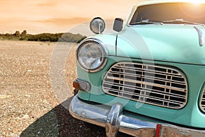 Headlight of a vintage classic car in the autumn golden sky at sunset time.