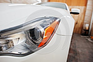 Headlight of white new luxury sport car in detailing garage