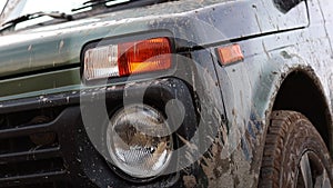 the headlights and grille of a dirty SUV. retro car off-road. Bad roads and camouflaged car