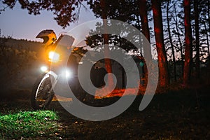 Headlights on, night forest. Adventure motorcycle, Motorcyclist gear, A motorbike driver looks, concept of active lifestyle, photo