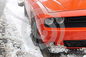 Headlights and soot of a red sports car on the snow. Beautiful Muscle car in the snow