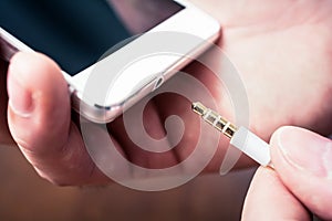 Headphone Jack Of A White Smartphone Gets Plugged In A White Headset Cable