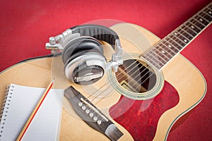 Headphone and Notebook and pencil on guitar