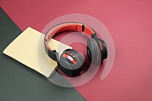 Headphone and notebook on red and black background