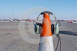Headphones of aircraft technician, who conducts preflight preparation of the aircraft, are put on an orange cone