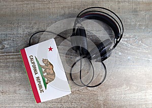 Headphones and book. The book has a cover in the form of California flag. Concept audiobooks. Learning languages