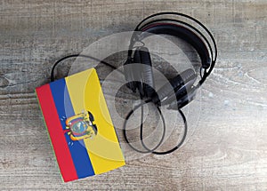 Headphones and book. The book has a cover in the form of Ecuador flag.