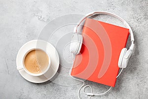 Headphones, book and cup of coffee on concrete surface