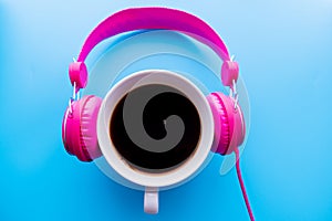 Headphones and coffee cup on blue background. Music concept. Top view with copy space