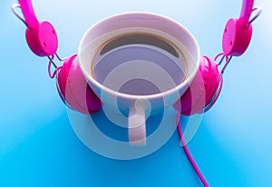 Headphones and coffee cup on blue background. Music concept. Top view with copy space