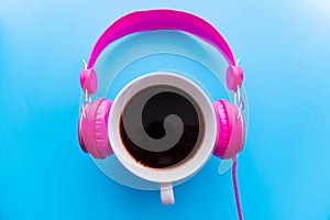 Headphones and coffee cup on blue background. Music concept. Top view with copy space