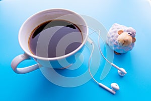 Headphones and coffee cup on blue desk table. Music concept. Top view with copy space