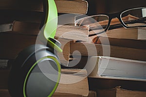 Headphones and eyeglasses sitting on stacks of books