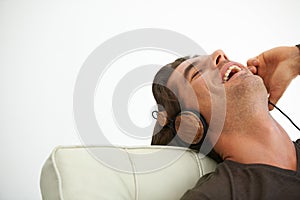 Headphones, happy and young man relaxing on chair in studio listening to music, radio or playlist. Smile, technology and