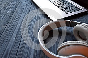 Headphones and laptop on the dark blue wooden desk.