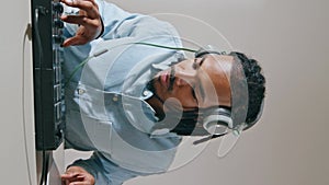 Headphones man using controller vertical closeup. Music producer working home