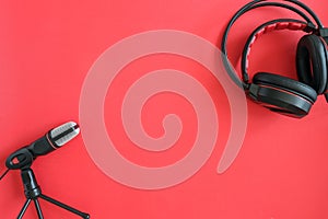 Headphones and microphone on red background. Concept music or podcast. Top view, flat lay Copy space