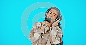 Headphones, microphone and woman singing isolated on blue background performance, voice and talent in recording studio