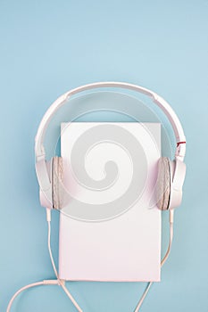 Headphones, mobile phone, idiobook, coffee cup on a blue background. The concept of leisure and learning, hobby. Listen to music,