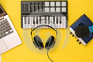 Headphones on music mixer, laptop and sound card on yellow background. The concept of workplace organization.