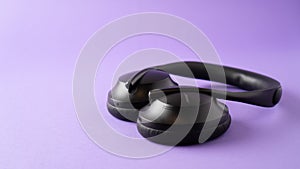 Headphones with noise canceling and the best microphone. black wireless headphones on purple background.