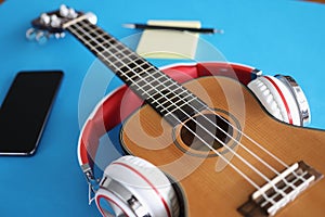 Headphones are putting on acoustic guitar on blue background closeup