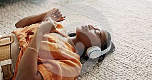 Headphones, relax and young woman on the floor in the living room listening to music or radio at modern apartment