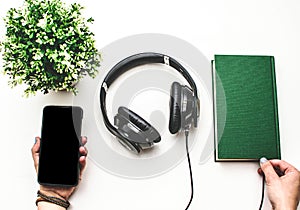 Headphones, smart phone, and book against white background