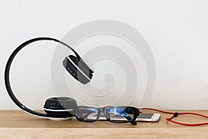 Headphones and smartphone on wood floor with glasses