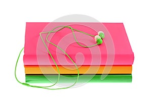 Headphones and stack of multicolored books on a white background