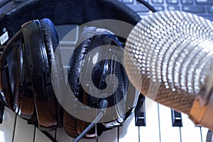Headphones on synth piano keyboard and head of condenser microphone. Making music concept