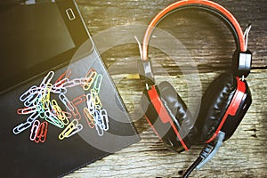 Headphones, tablets and notebooks on wooden background.