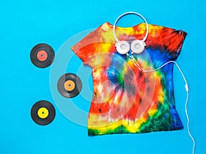 Headphones, vinyl discs and a tie dye t-shirt on a blue background. Flat lay. Pastel color.