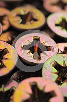 The heads of the screws, light, anodized close-up. Dark red and green vertical illustration. Hardware, fasteners, materials for