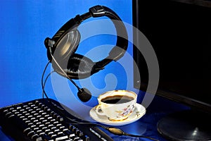 Headset computer-headphones, microphone, monitor, keyboard and a Cup of coffee for vivacity. Computer headset for online store,